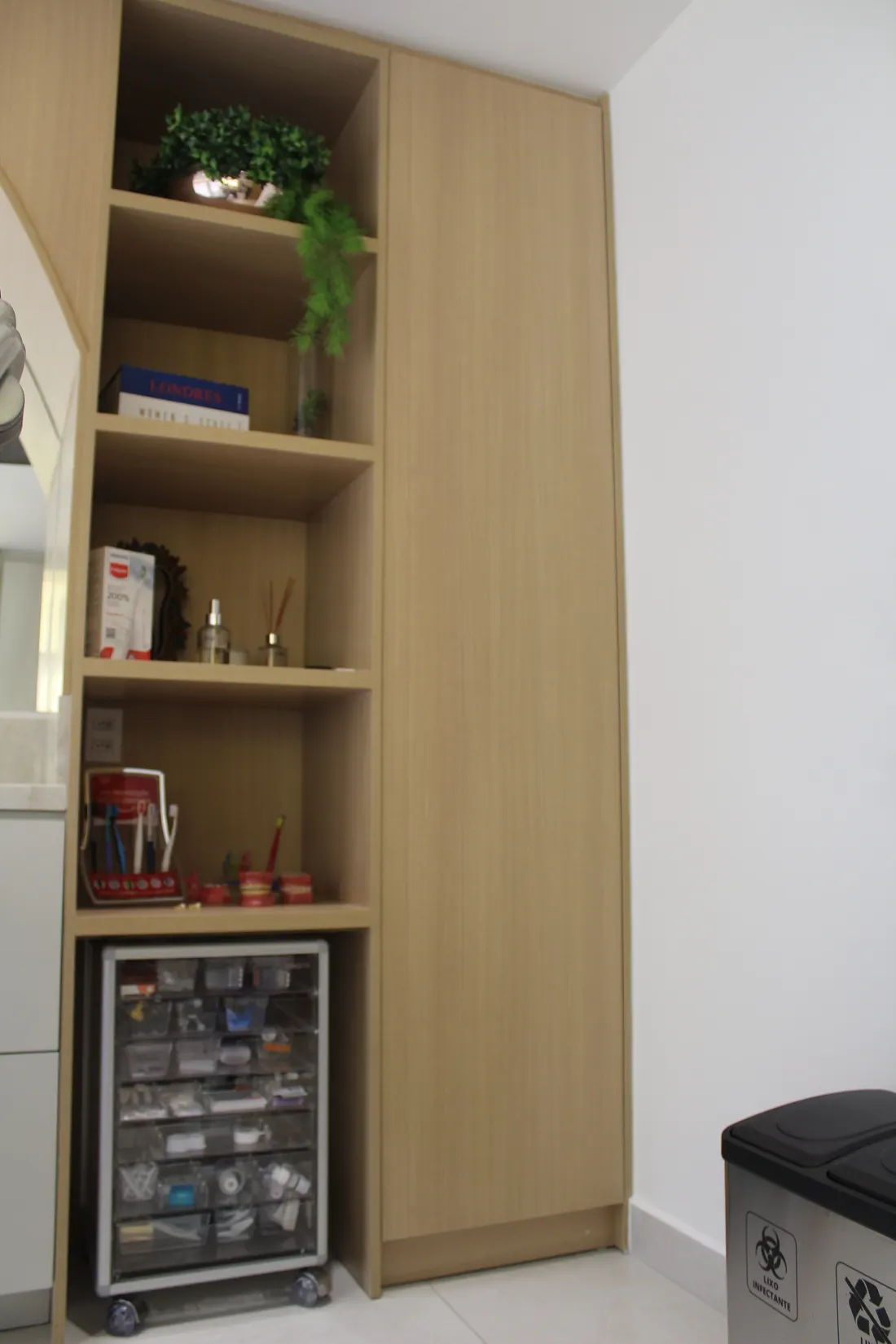 Armário planejado com nichos abertos e espaço para gaveteiro de materiais na sala clínica do consultório