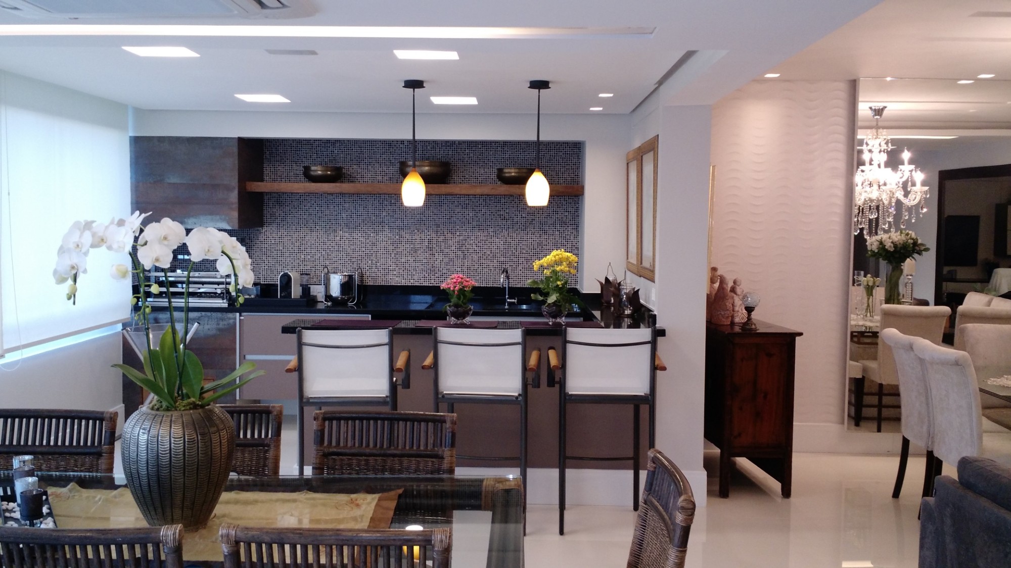 Cozinha gourmet integrada à sala de jantar, com bancada preta, pastilhas e pendentes, em apartamento projetado e executado pela LaArc